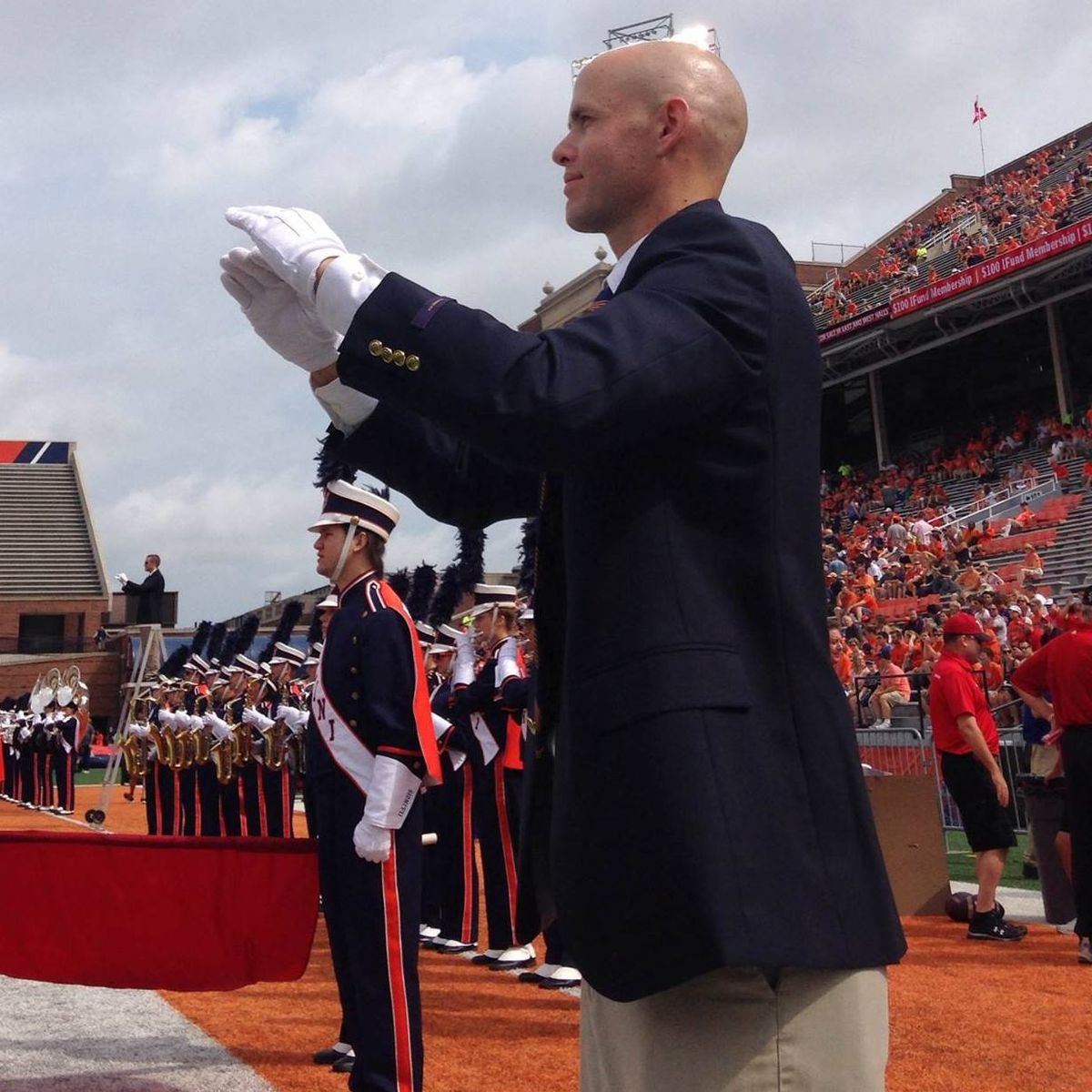Dr. Shuey conducting a marching band in a football stadium
