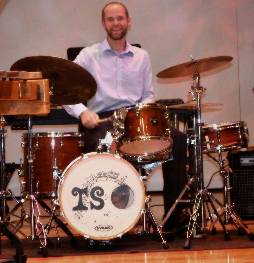 Dr. Shuey smiling behind a drum set