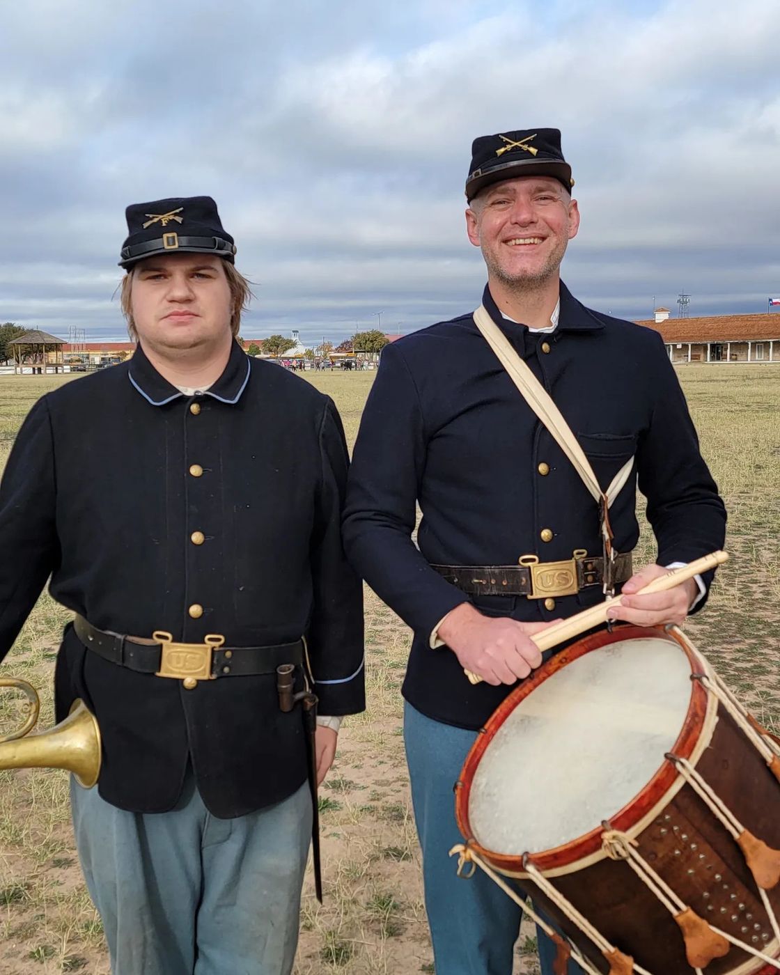 Dr. Shuey in period uniform with a field drum at Fort Concho, beside a bugler