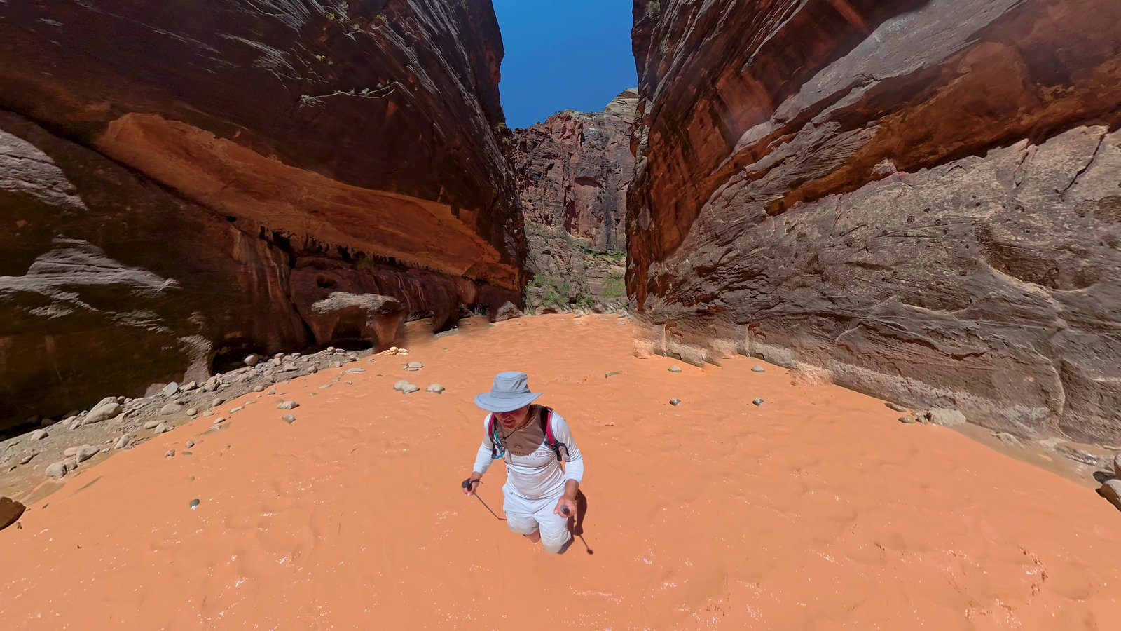 Dr. Shuey alone in the Zion Narrows, wading orange floodwater between red canyon walls
