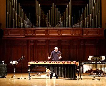Dr. Shuey playing marimba on a concert stage in front of organ pipes