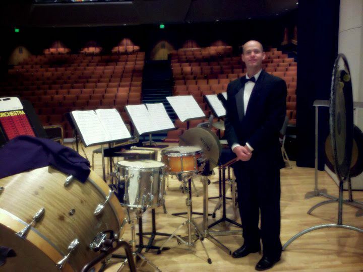 Dr. Shuey on stage beside a percussion setup