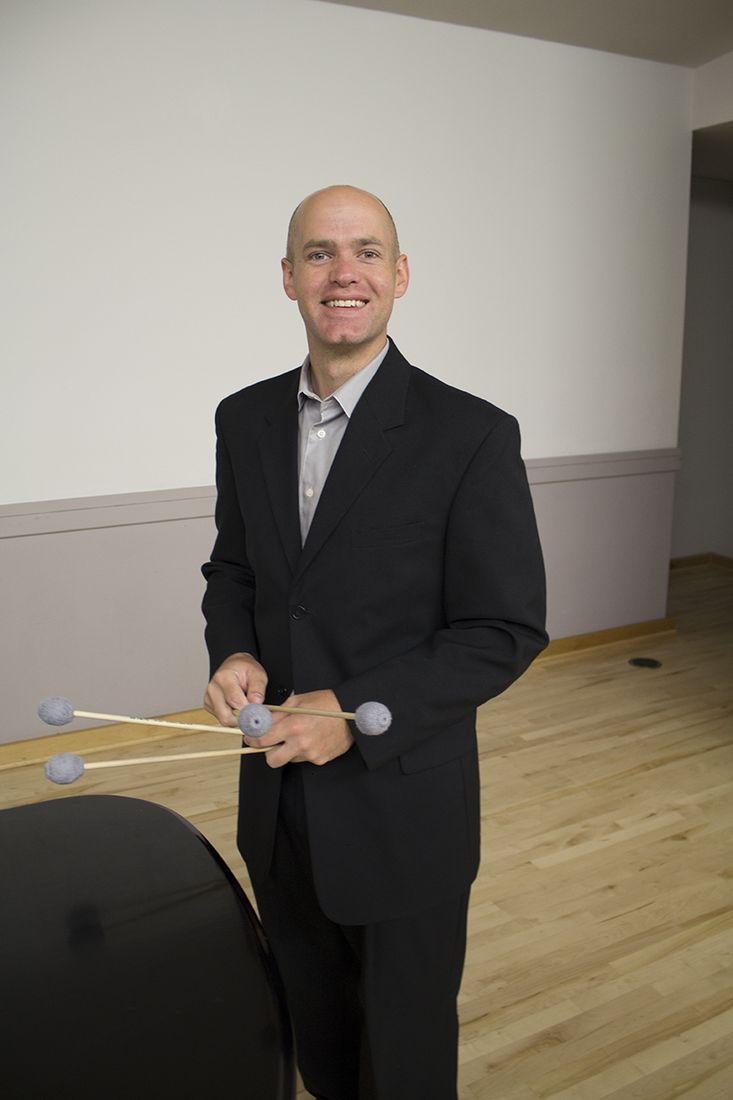 Trent Shuey in a suit holding marimba mallets