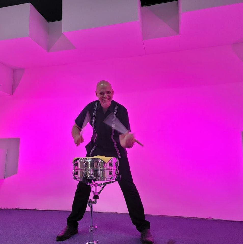 Dr. Shuey playing snare drum on a stage lit pink